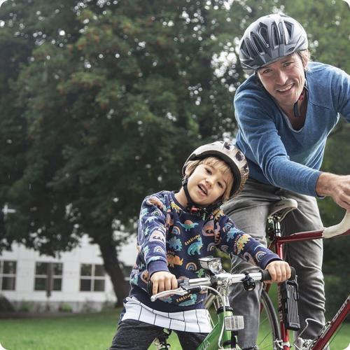 Mädchen und Mann mit dem Fahrrad lächeln in die Kamera.